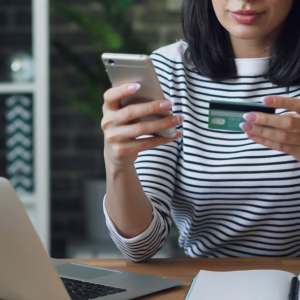Mulher usando cartão e celular para participar de promoção comercial.