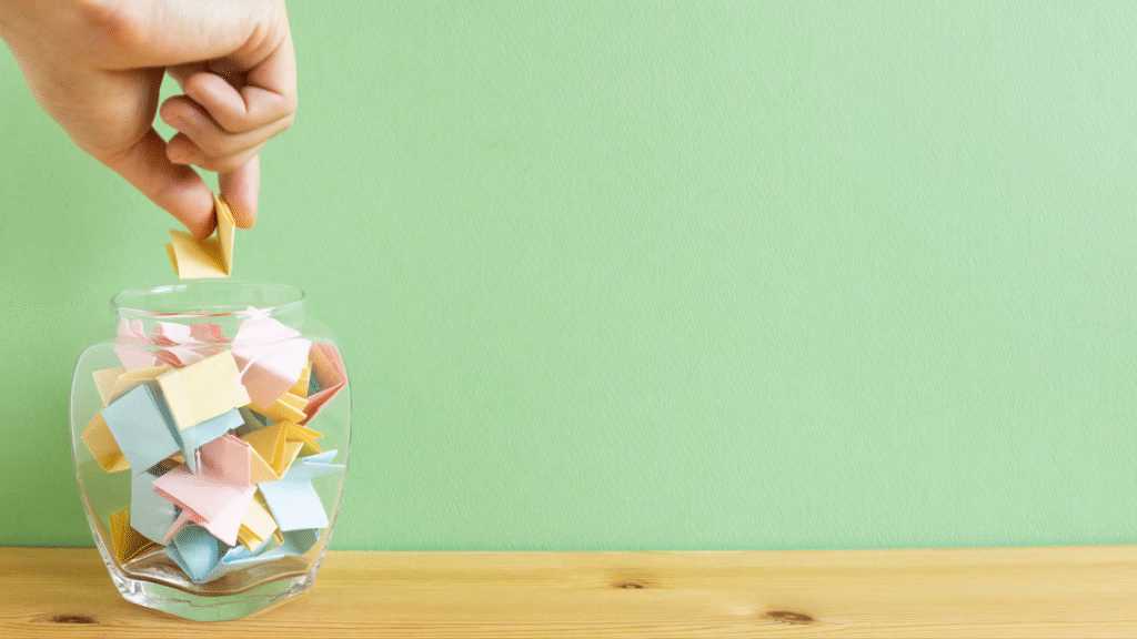 Mão sorteando um papel colorido em pote de vidro, simbolizando a escolha de ganhadores em promoção do tipo modalidade assemelhada a concurso.