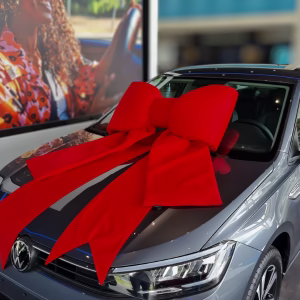 Carro exposto com laço vermelho, ilustrando prêmios de promoções comerciais autorizadas no Brasil.